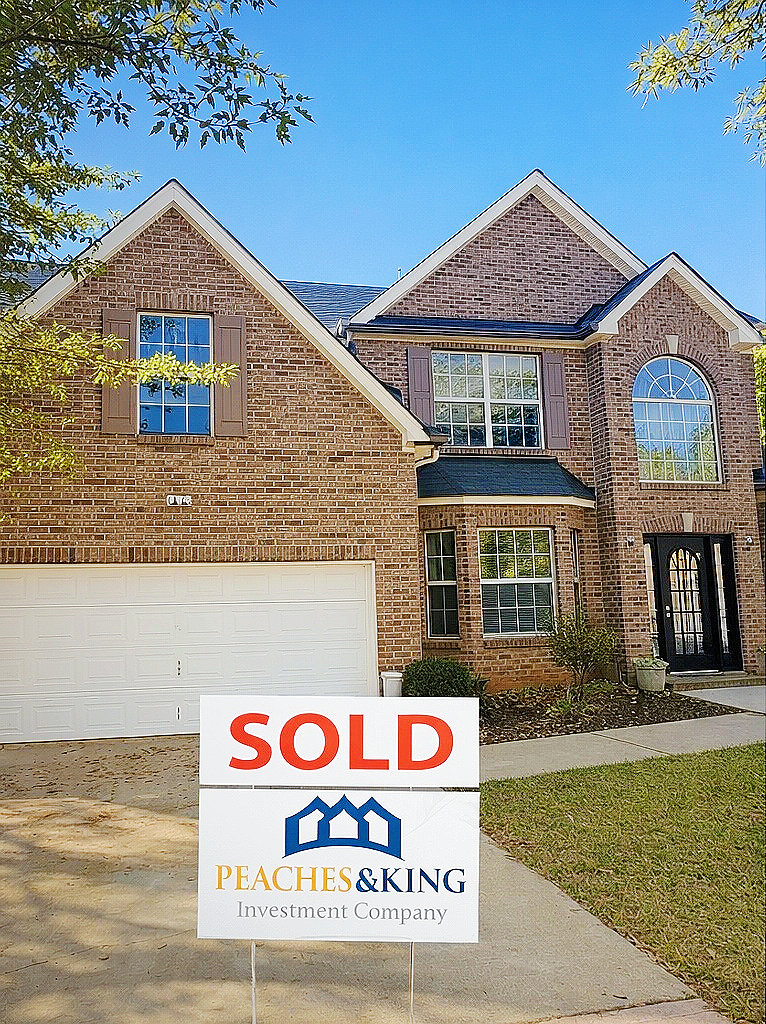A brick home showcased by Peaches & King, with the original sold sign.